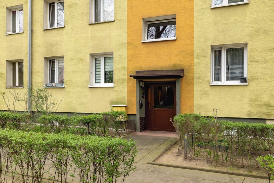 View of the entrance to the cage, next to neat green shrubs.