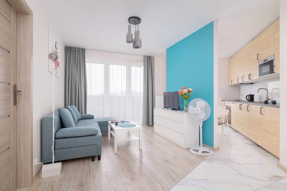 Stylish and modern living room with kitchenette, dining table with chairs, coffee table, and television.