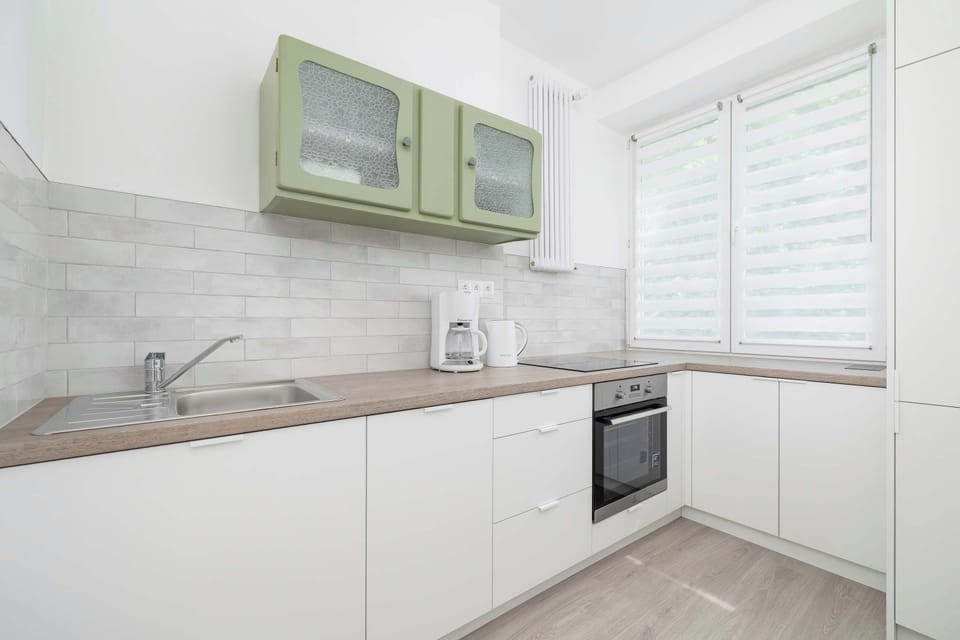 A bright kitchen with green cabinets, a wooden countertop and full equipment encourages daily cooking.