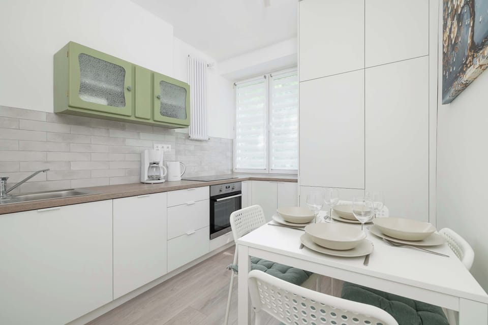 A functional kitchen with a dining area and green cabinet fronts invites shared cooking and meal enjoyment.