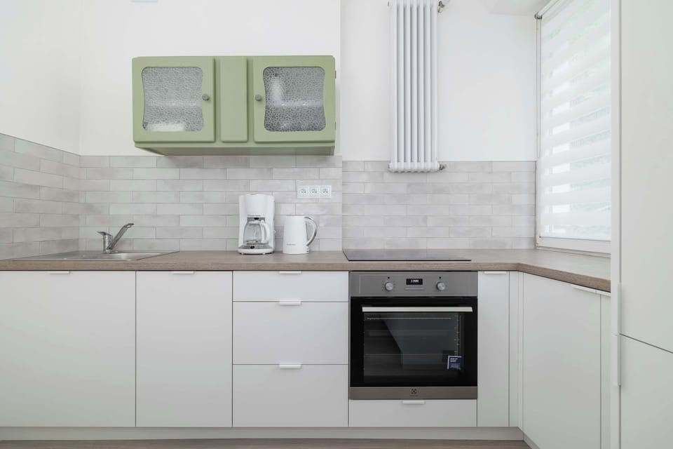 A kitchen corner with a window, coffee maker and oven invites you to enjoy morning coffee and cook together.