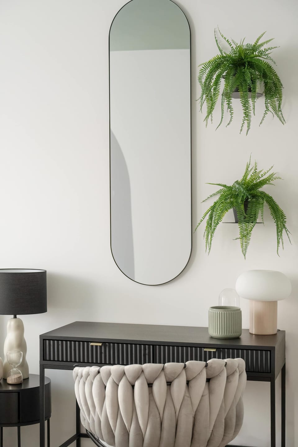 Close-up of desk and upholstered chair. Above the desk is an oval large mirror.