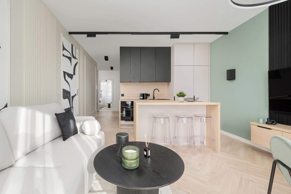 A combined kitchen and dining area with wooden flooring, a round dining table, and stylish lighting.
