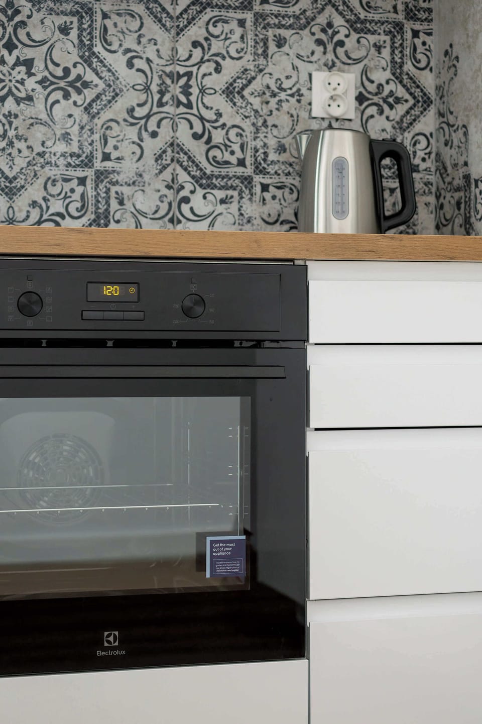 A closer view of the kitchen focusing on the modern oven, backsplash, and practical design elements.