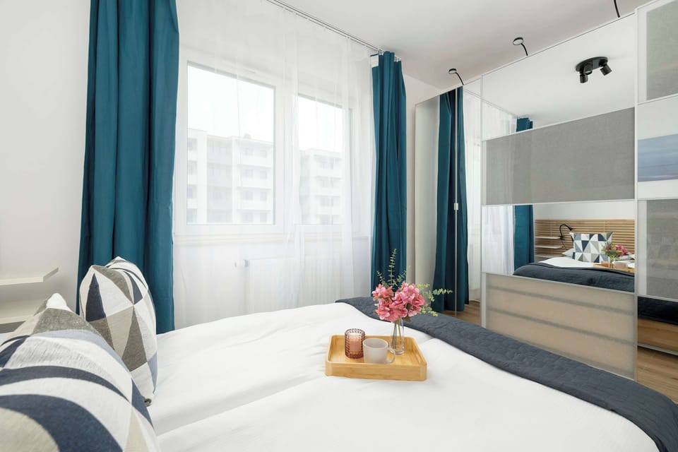 A cozy bedroom view showcasing the bed with vibrant throw pillows and a large window bringing in light.