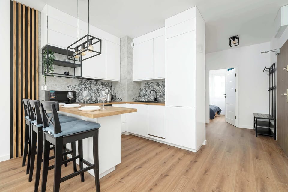 An open-concept kitchen with white cabinets, a black countertop, and bar stools at the counter, combining practicality with style.