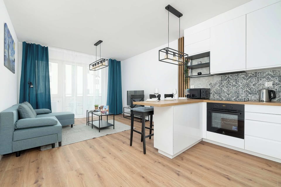 An open-plan design that seamlessly connects the living room to the kitchen area with consistent wooden flooring.