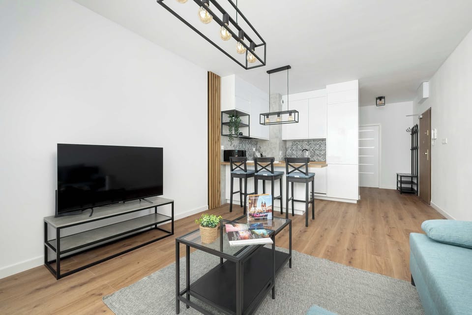  A wider perspective of the living room displaying the sofa, TV setup, and part of the dining area in a contemporary style.
