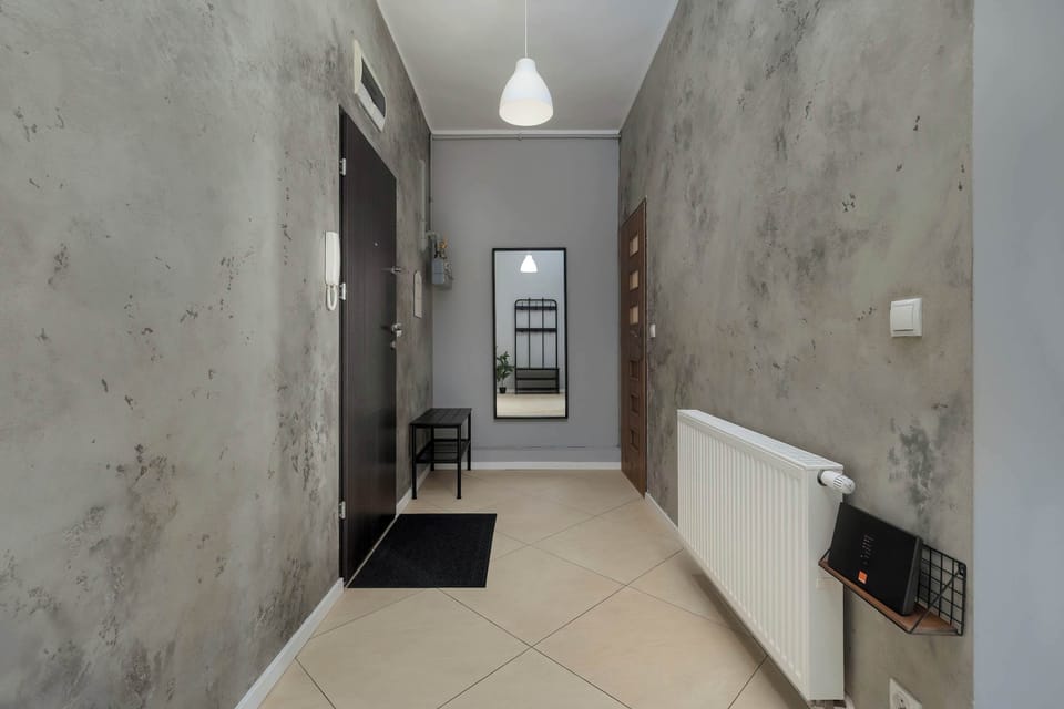 A hallway with a concrete finish and mirror at the end, leading to different rooms.