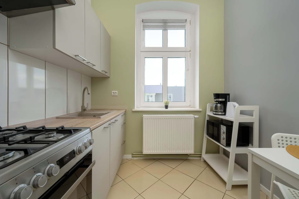 A functional kitchen with white cabinets, gas stove, and natural light from the window.
