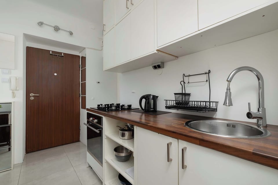 Fully equipped kitchenette with with light-colored cabinets and a wooden countertop.