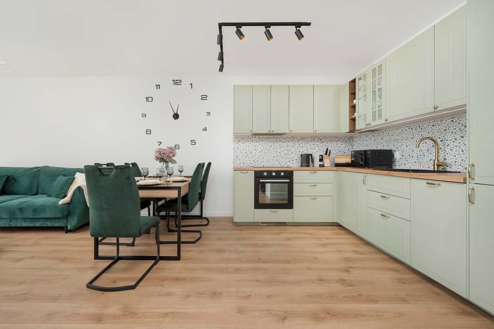 A complete view of the kitchen with pastel cabinets, a wooden countertop, and decorative terrazzo tiles above the counter.