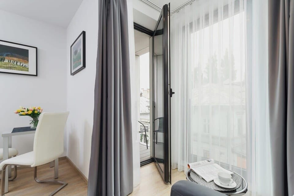 A comfortable bedroom with a double bed and access to a small balcony. The balcony view offers a glimpse of the surrounding area and natural light fills the room.