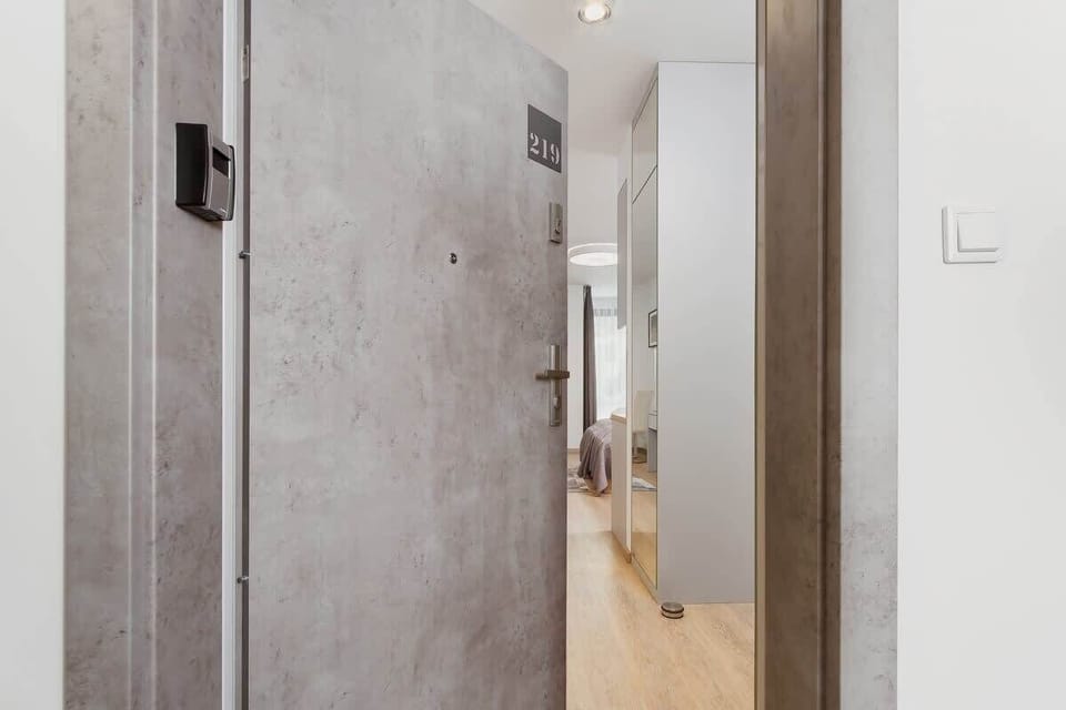 A solid, modern entrance door with a sleek handle and neutral colors. The entryway is well-lit and provides a secure, welcoming feel to the apartment.