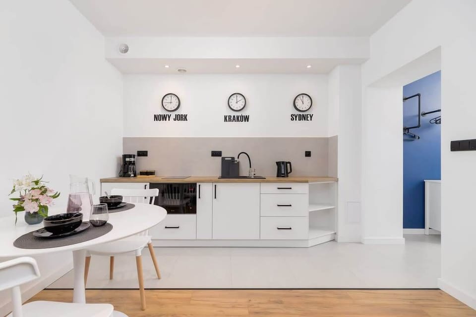 A dining area with a wall-mounted clock, round mirror, and contemporary blue decor.