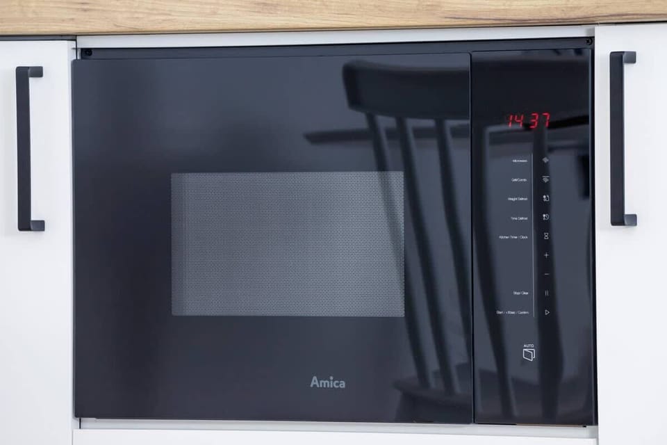A close-up of the kitchen counter showcasing a modern built-in microwave and clean finishes.
