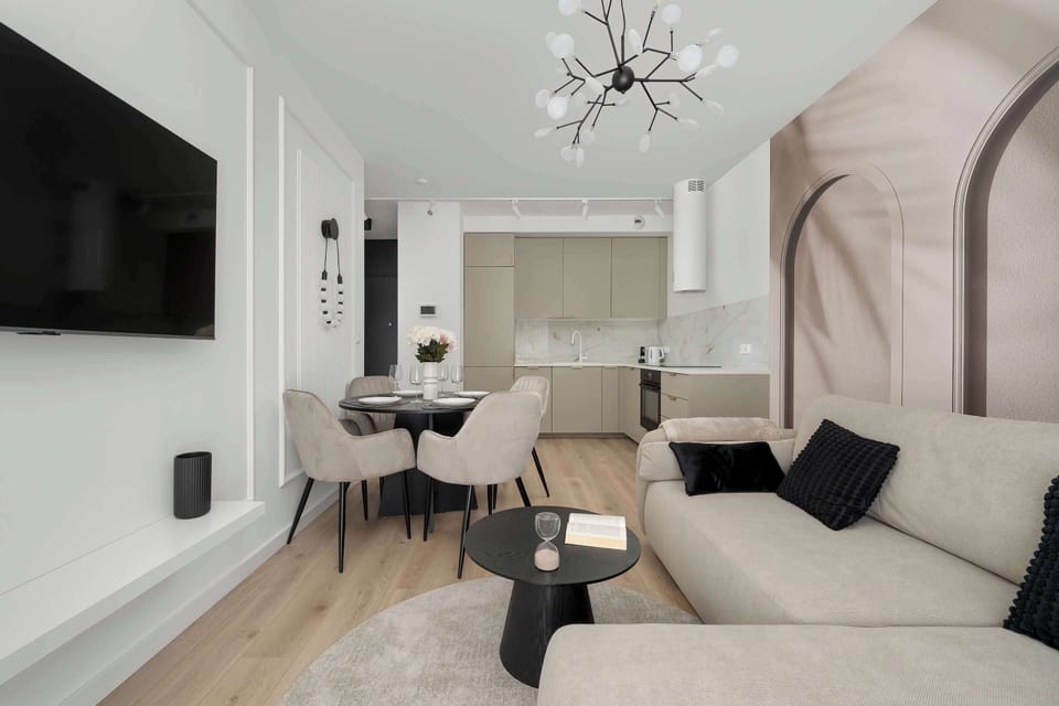 The living area has a comfortable sofa, an elegant coffee table and a flat-screen TV. Living room combined with kitchenette and dining area.