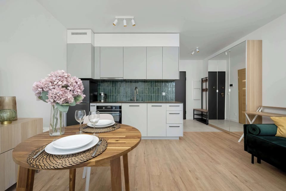 A dining area with a round wooden table, chairs, and a TV on a white stand, part of the open-plan space.