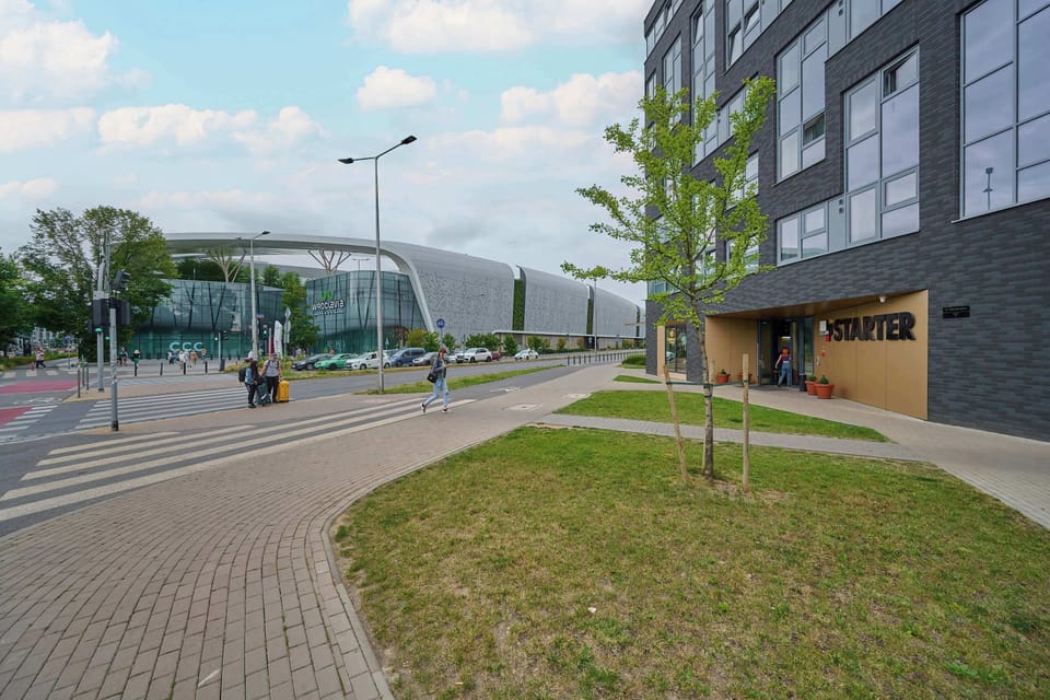 An exterior view of the modern apartment complex, featuring a contemporary design with large windows and a neatly landscaped walkway.

