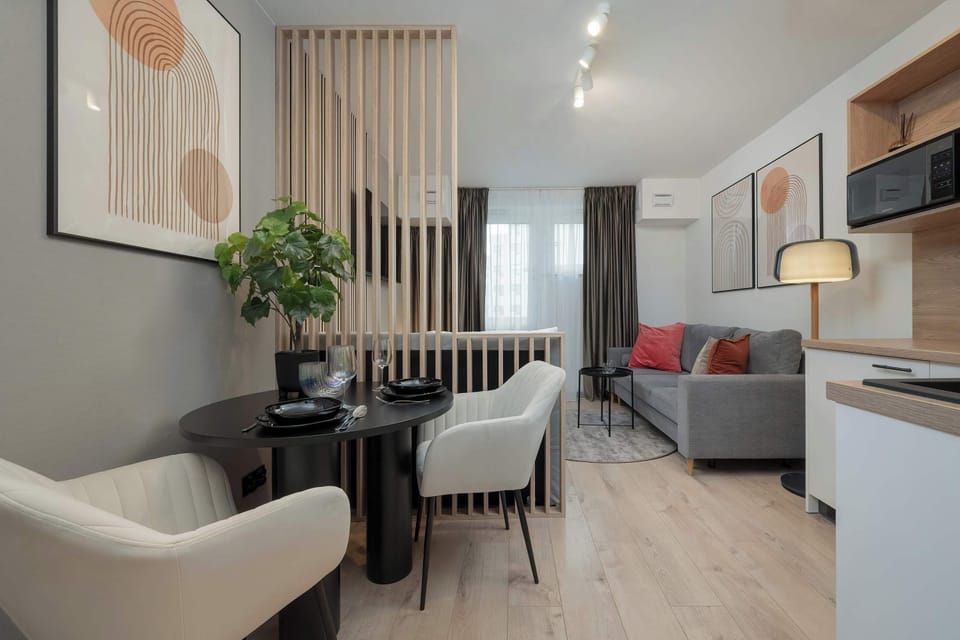 A different angle of the dining area featuring a black round table and plush beige chairs against a wooden slat backdrop.

