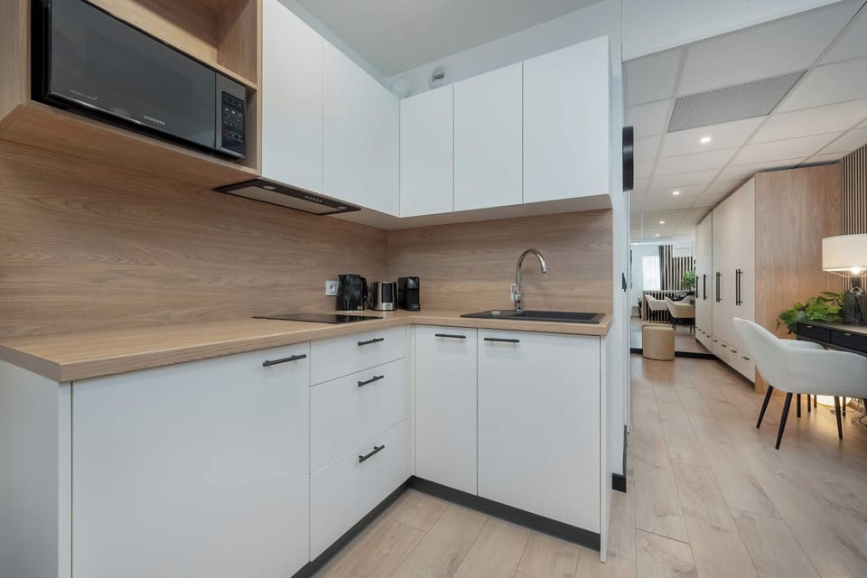A compact, fully equipped kitchen with white cabinets, wooden countertops, and modern appliances for a sleek look.

