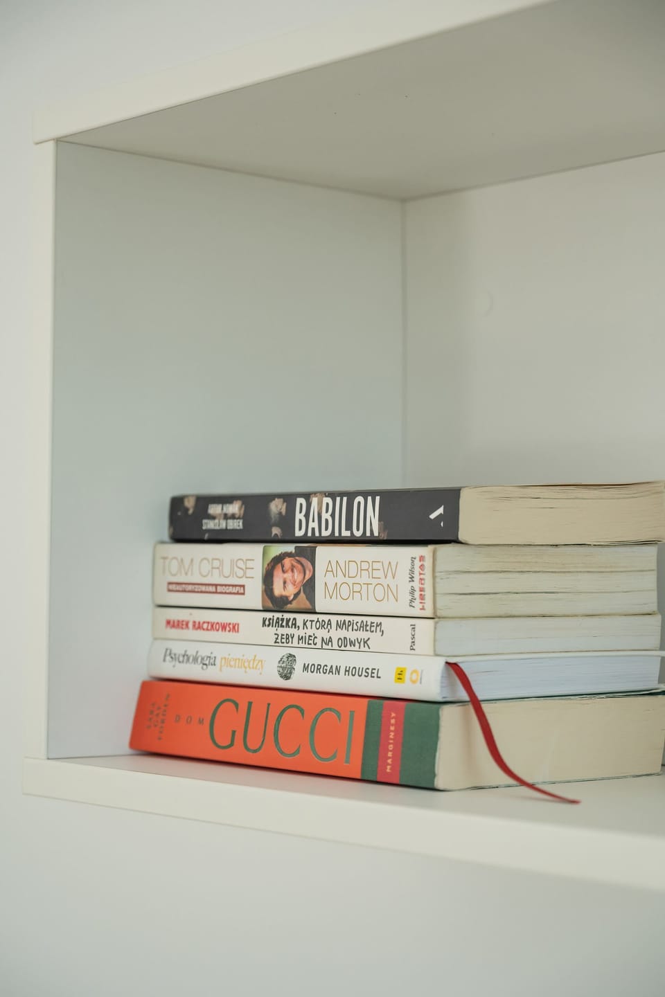 A close-up of a small decorative bookshelf with books and subtle decor pieces. The minimalist design blends well with the overall clean aesthetic of the apartment.