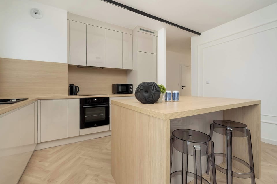 Another angle of the kitchen showing a built-in oven and ample storage space. The light wood floor adds warmth to the space.