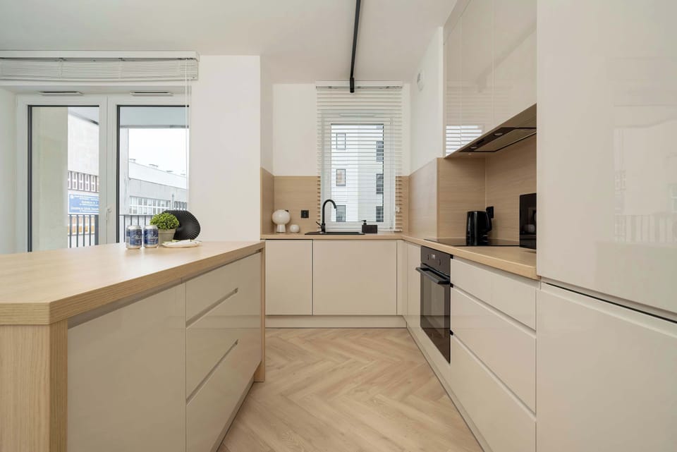 A kitchen with white cabinets, a wooden countertop, and integrated appliances. The design is sleek and functional.