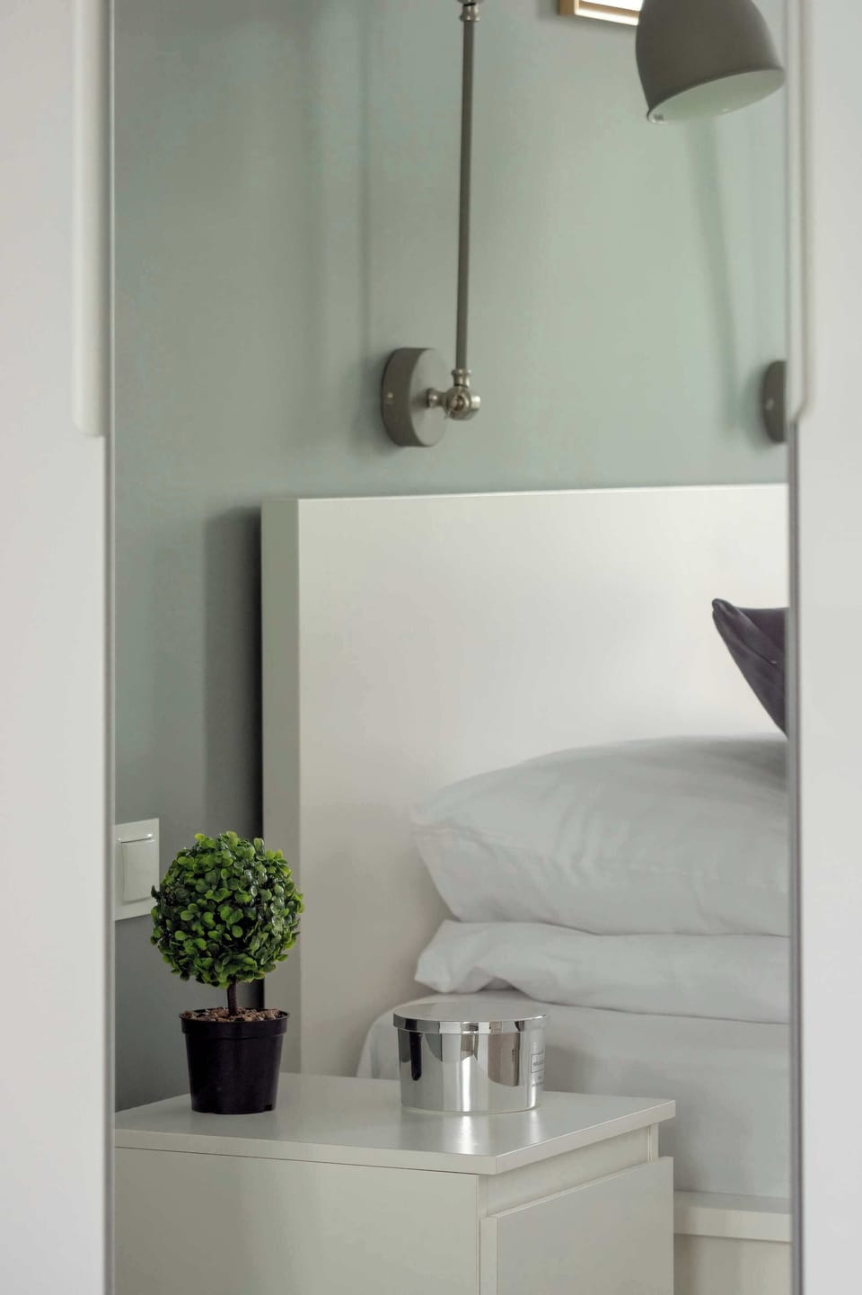 A bedside cabinet with decor and wall lamps creates a cozy corner in an elegant style.