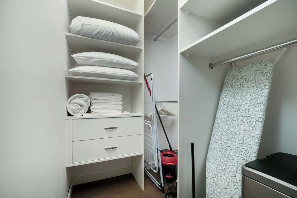 A closet area with shelves and storage, showing folded towels and clothes.