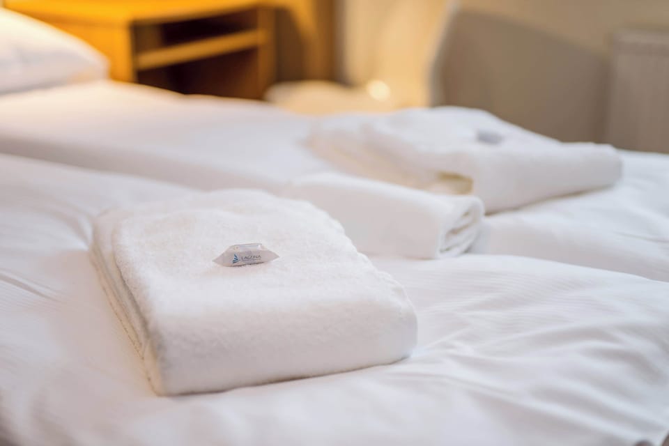A close-up of neatly folded towels on the bed, emphasizing the cleanliness and comfort provided for guests.