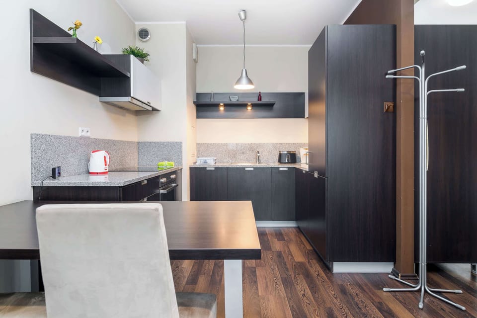 A modern kitchen with dark cabinets and a speckled gray countertop. The kitchen is equipped with a stovetop and extractor fan, with plenty of storage space.