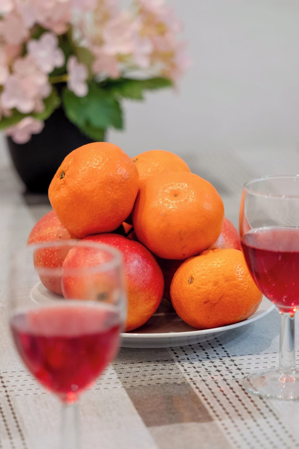 A close-up of a dining table with a bowl of fresh oranges and a glass of juice.