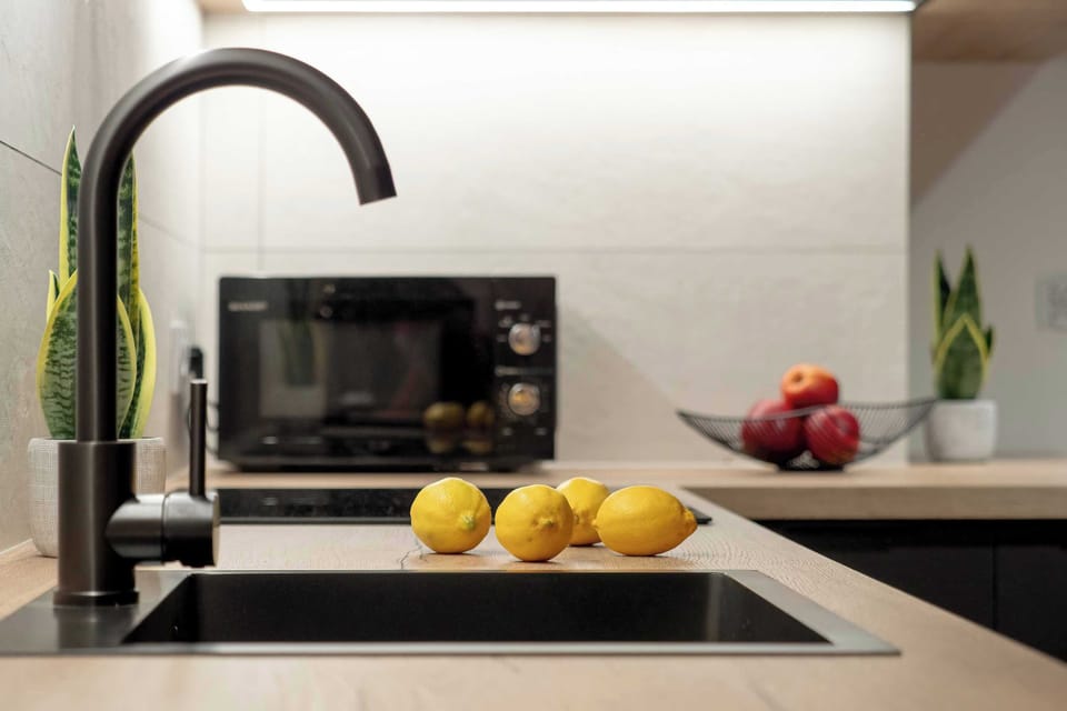 Modern kitchen corner with a built-in microwave, a sleek faucet, and fresh fruits placed on the counter.