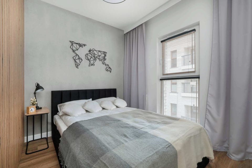 Similar perspective of the bed and window, with light grey walls and a peaceful vibe.