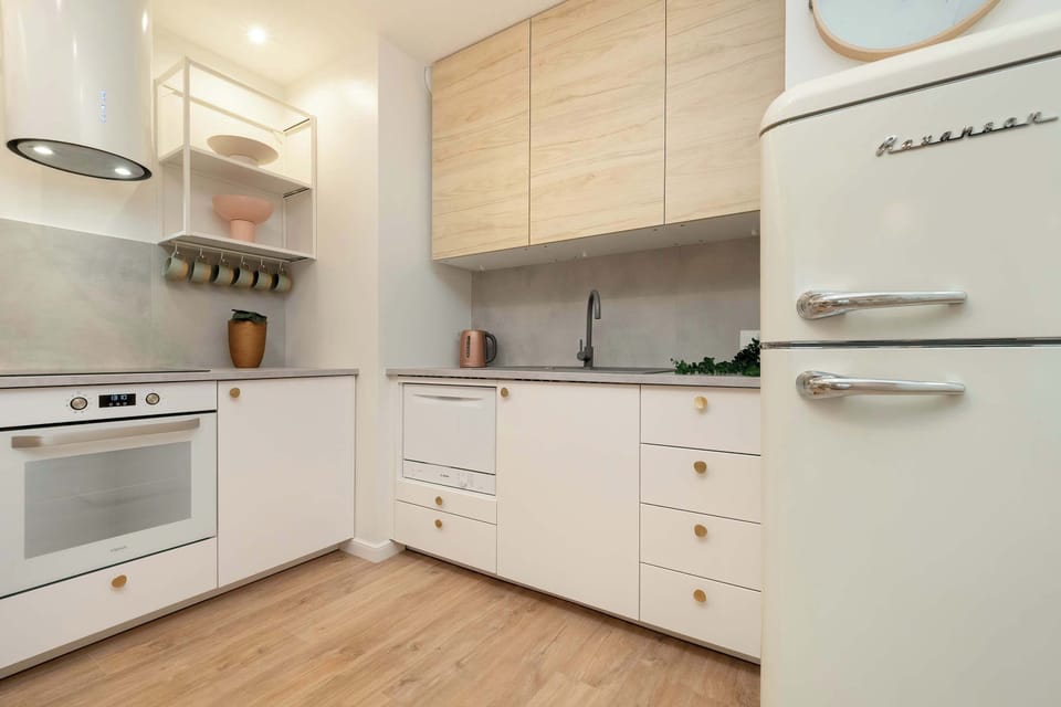 A modern kitchenette with white cabinets, wood countertops, and some small decorative plants.