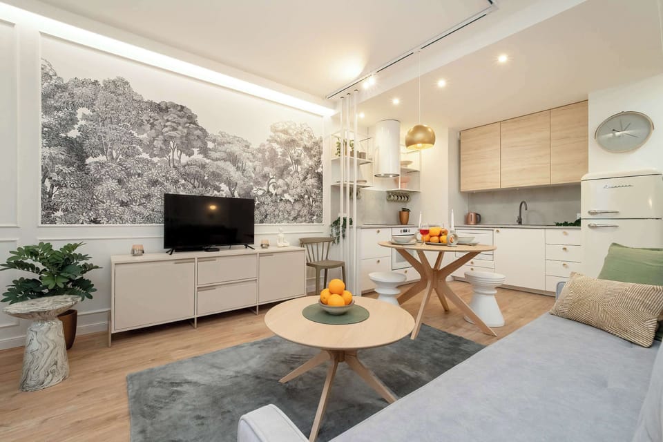 A bright living space with a soft sofa, decorative wallpaper, and a small table with a few decorative items.
