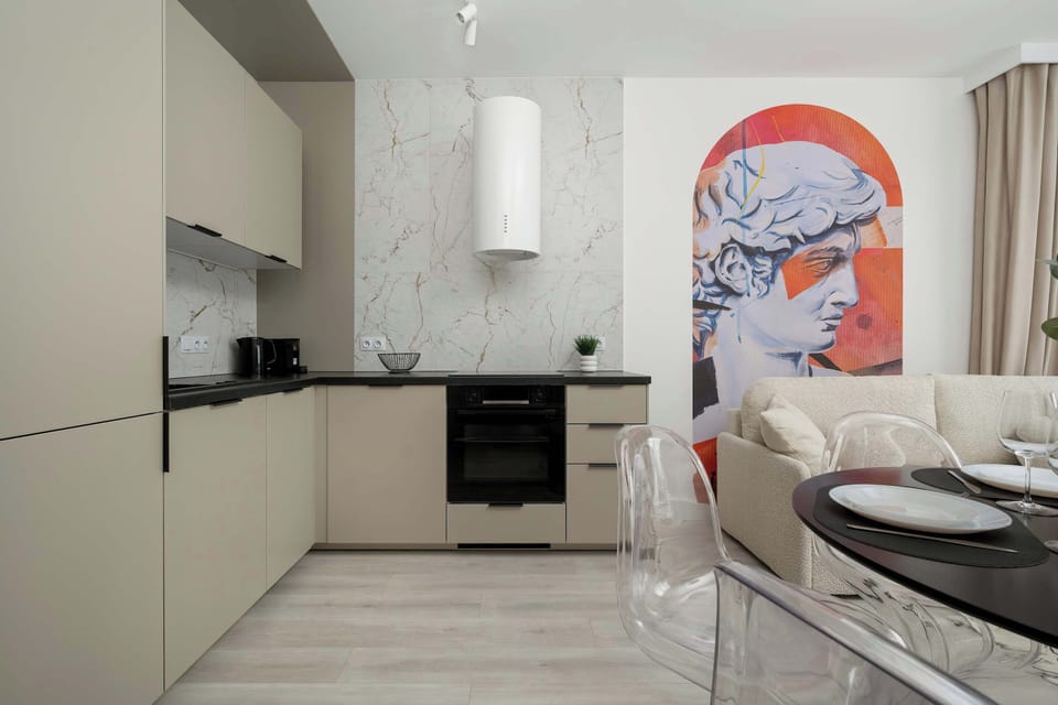 A functional kitchenette with cabinets, modern appliances (induction hob, oven, fridge with freezer, microwave, dishwasher) and a dining room with a round table and chairs.