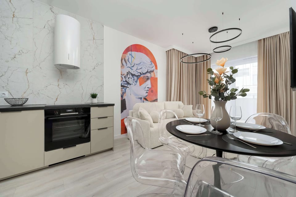 Dining room with round table, transparent chairs and kitchenette.
