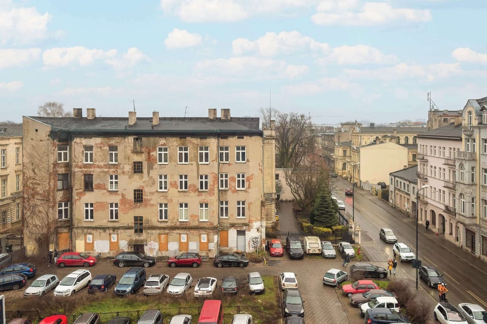 An urban street view with older residential buildings and trees lining the area.