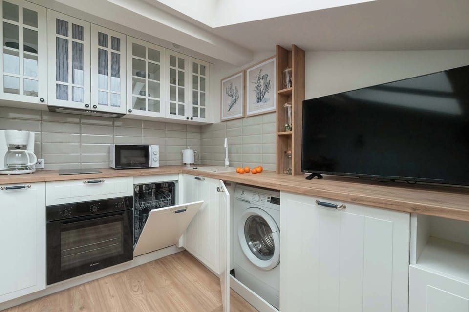 A section of the kitchen including a washing machine under the counter and cabinets for organization.