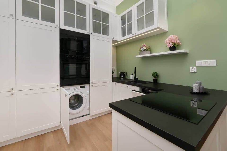 Built-in oven and additional storage in white cabinetry, contrasted by a black countertop.

