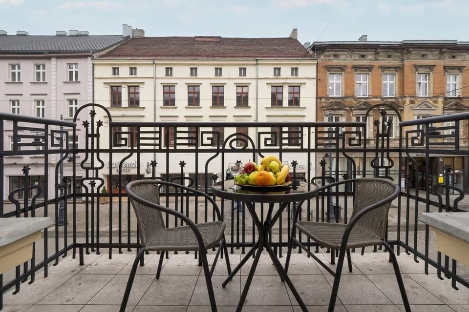 Balcony overlooking historic buildings, furnished with a black table and chairs, plus a fruit bowl centerpiece.

