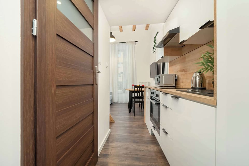 A clean hallway featuring wooden doors and cabinetry leading into the kitchen area.