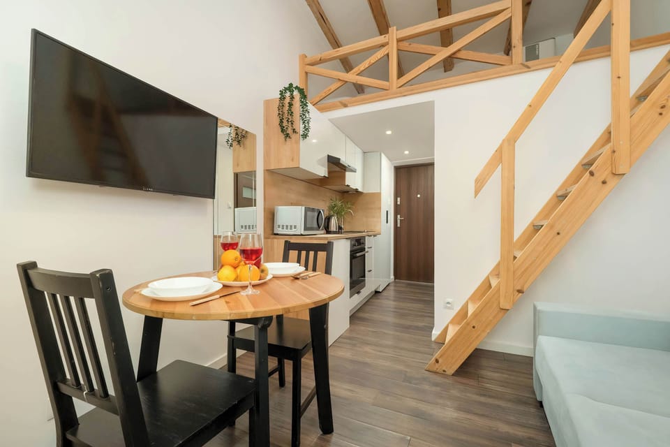  A modern living room with a gray sofa, a round dining table, and a wooden staircase leading to an upper level.