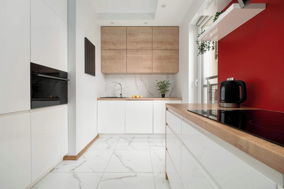 Compact kitchen with built-in appliances and red accent wall – Functional layout in bold tones.