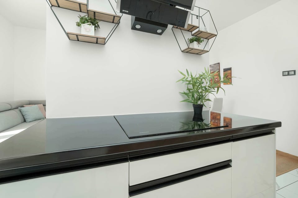 A sleek, contemporary kitchen featuring pristine white cabinetry and warm wood accents.
