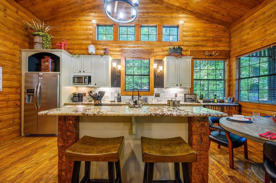 Warm cabin kitchen with granite island, modern appliances, and rustic charm.
