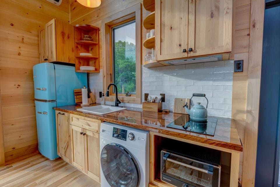 Closer view of Willow`s kitchen with induction cooktop, open shelving, and a vintage-style blue fridge beside the sink.