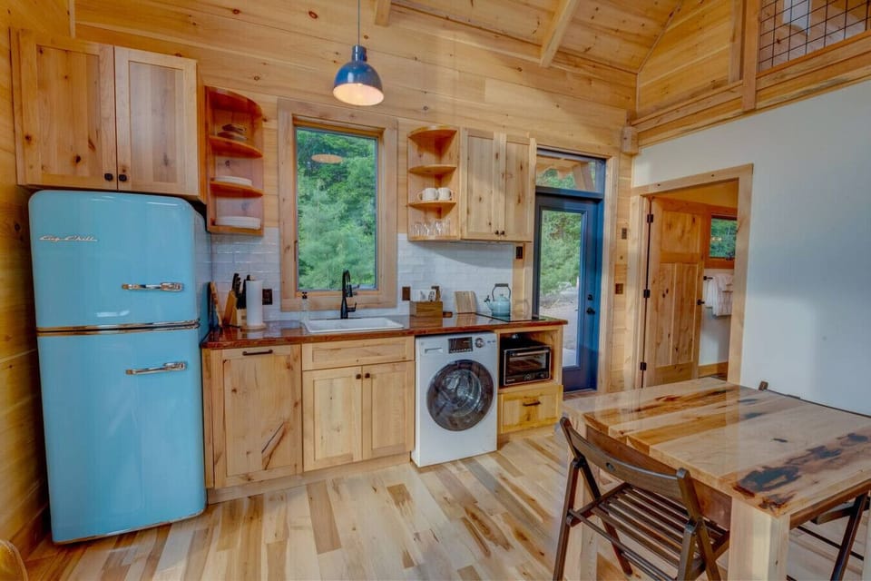 Kitchen in the Willow Cabin, with natural pine cabinetry, a blue retro-style fridge, and compact modern appliances.